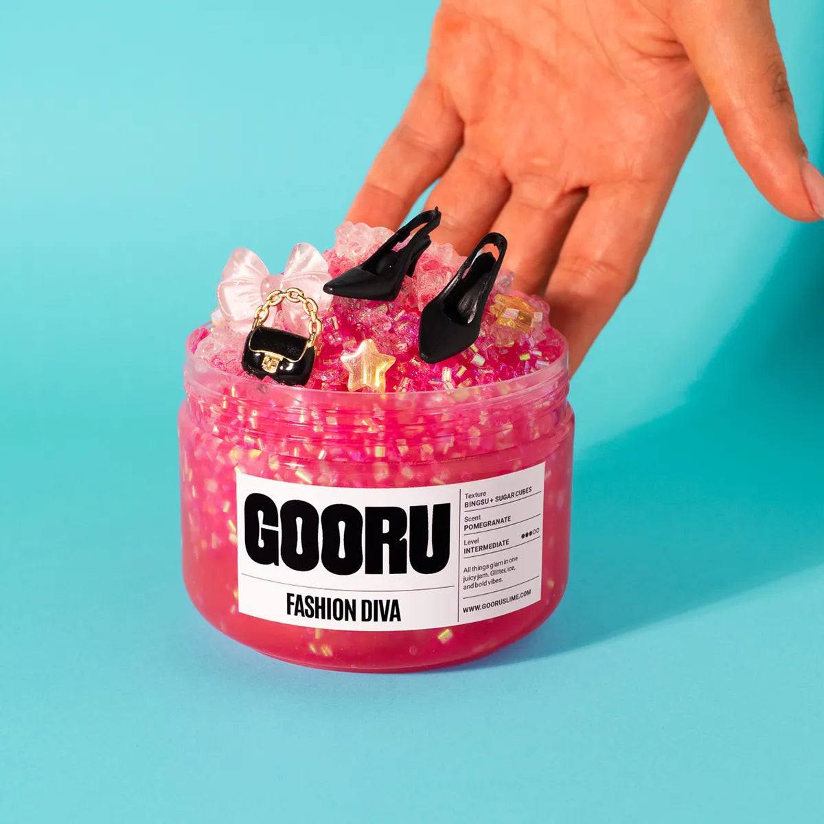 Pink slime jar with decorative items and a hand holding it against a blue background, featuring the brand 'GOORU'.