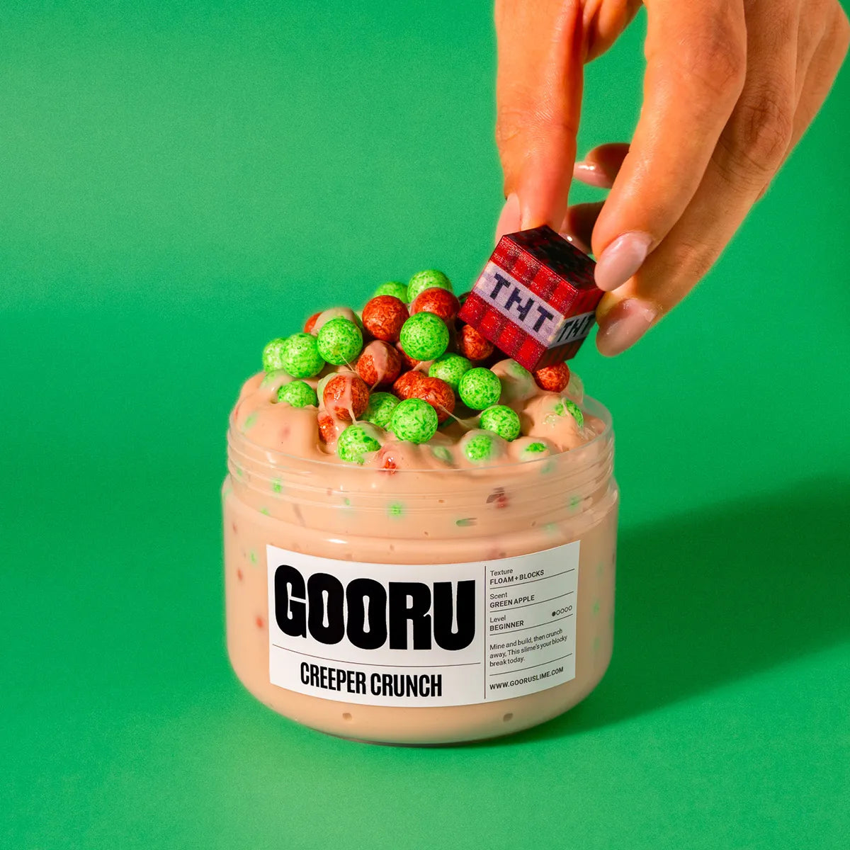 Jar of 'GOORU Creeper Crunch' slime with a hand holding a 'TNT' block against a green background
