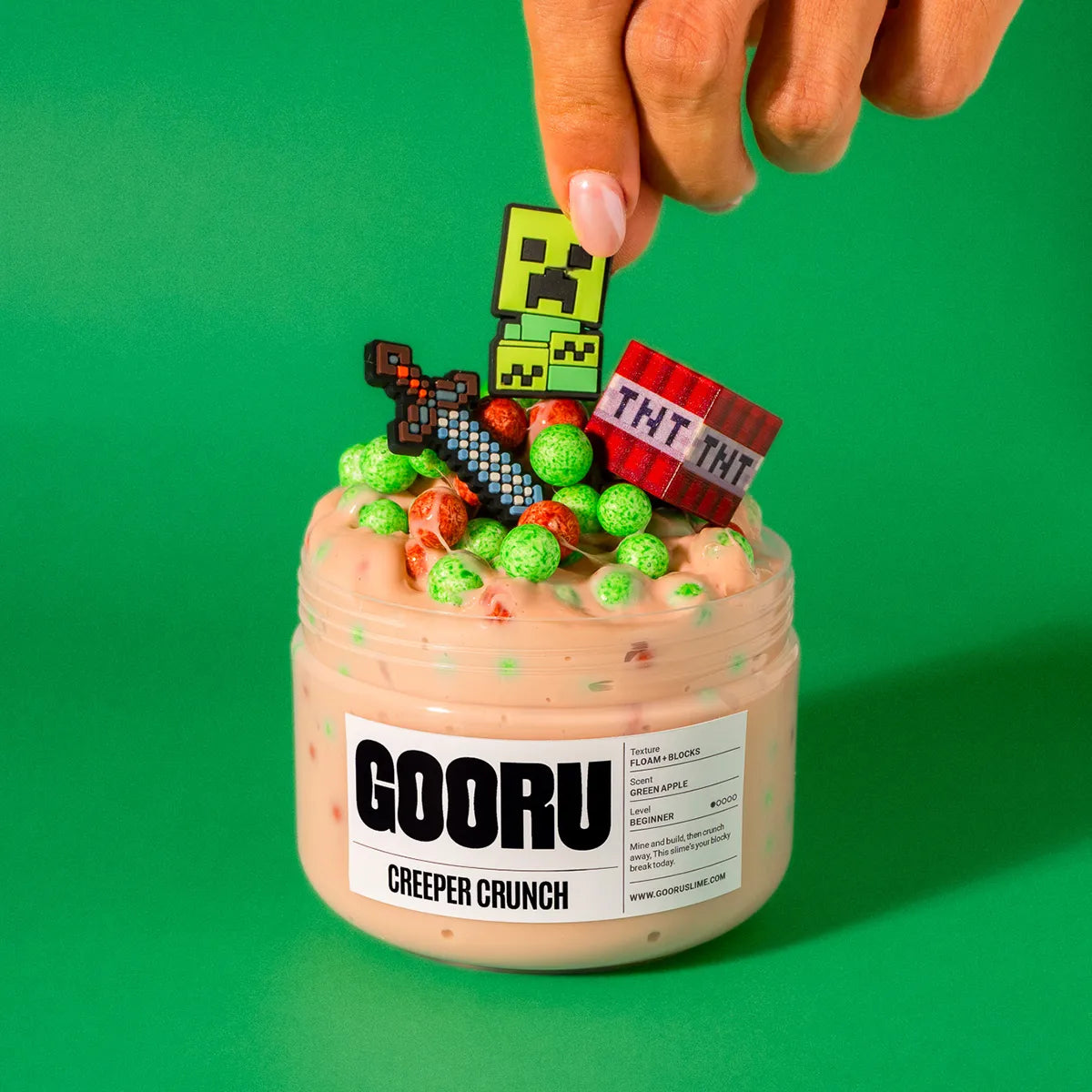 Jar of 'GOORU Creeper Crunch' slime with colorful Minecraft-themed figurines on a green background