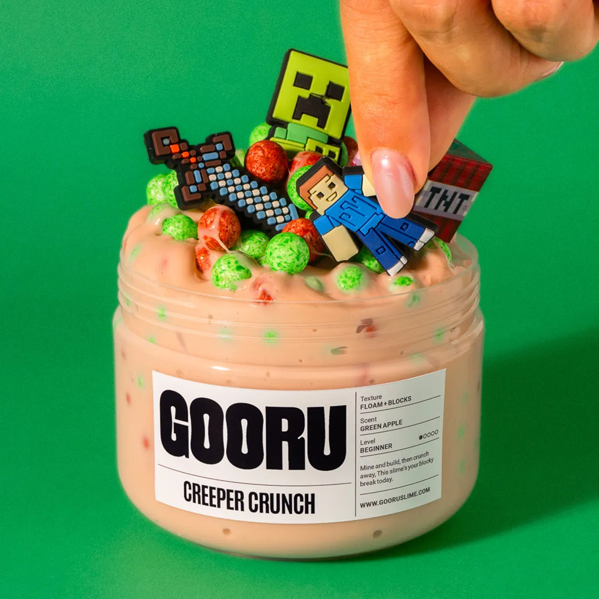 Jar of 'GOORU Creeper Crunch' slime with colorful Minecraft-themed figurines on a green background
