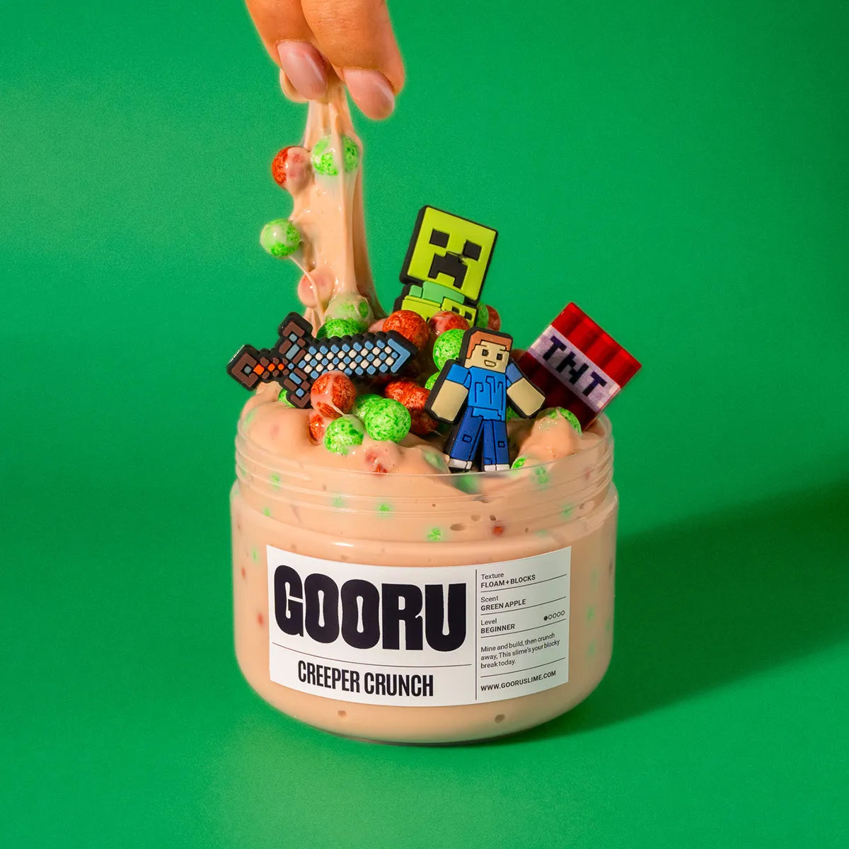 Jar of 'GOORU Creeper Crunch' slime with colorful candy pieces on a green background