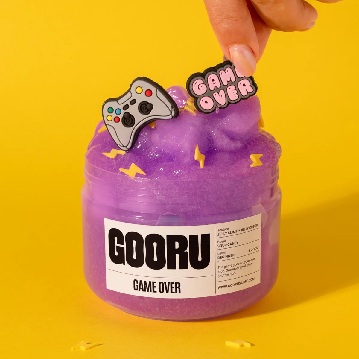Purple slime jar with 'GOORU' label and gaming-themed decorations on a yellow background