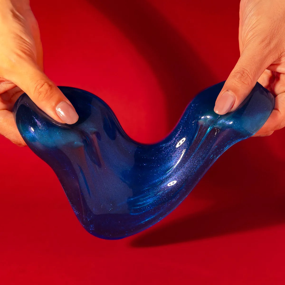 Blue slime held by hands against a red background
