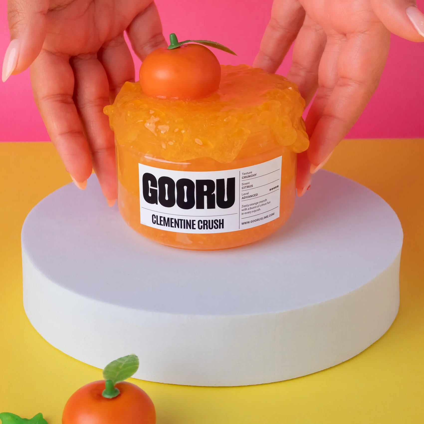 Orange jelly-like product with a label on a pink and yellow background
