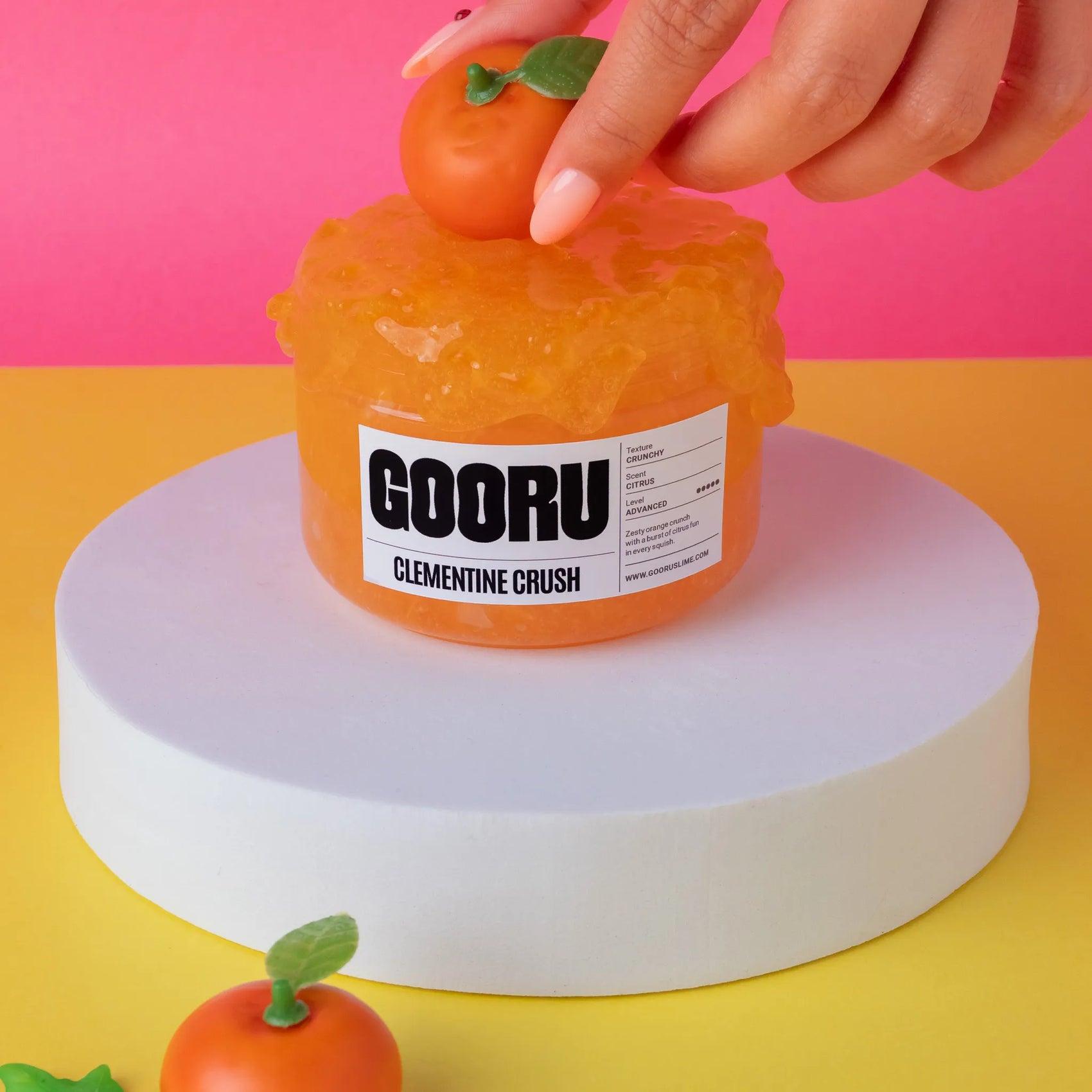Orange jelly-like product with a label on a pink and yellow background