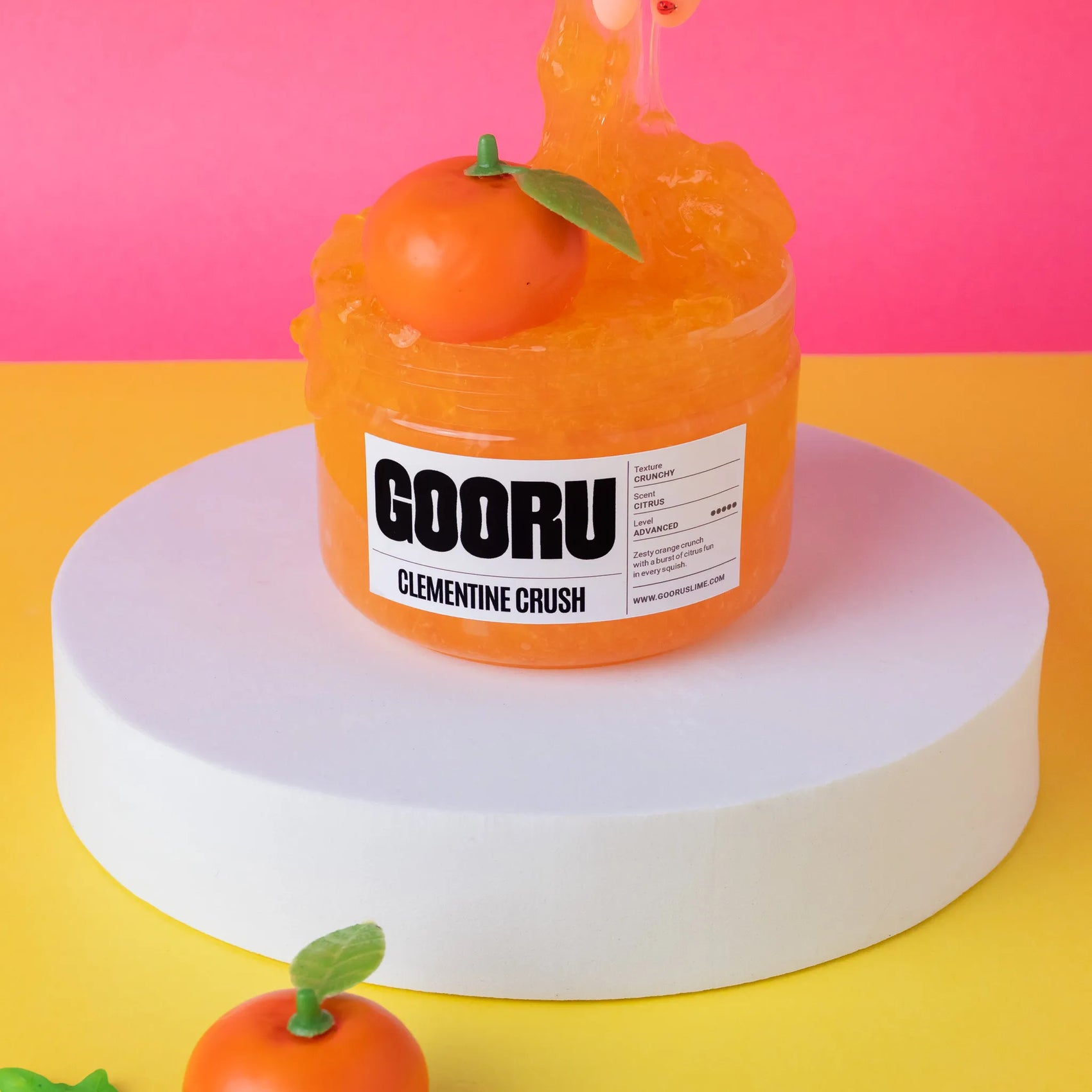 Orange slime container with a Clementine Crush flavor label on a pink and yellow background