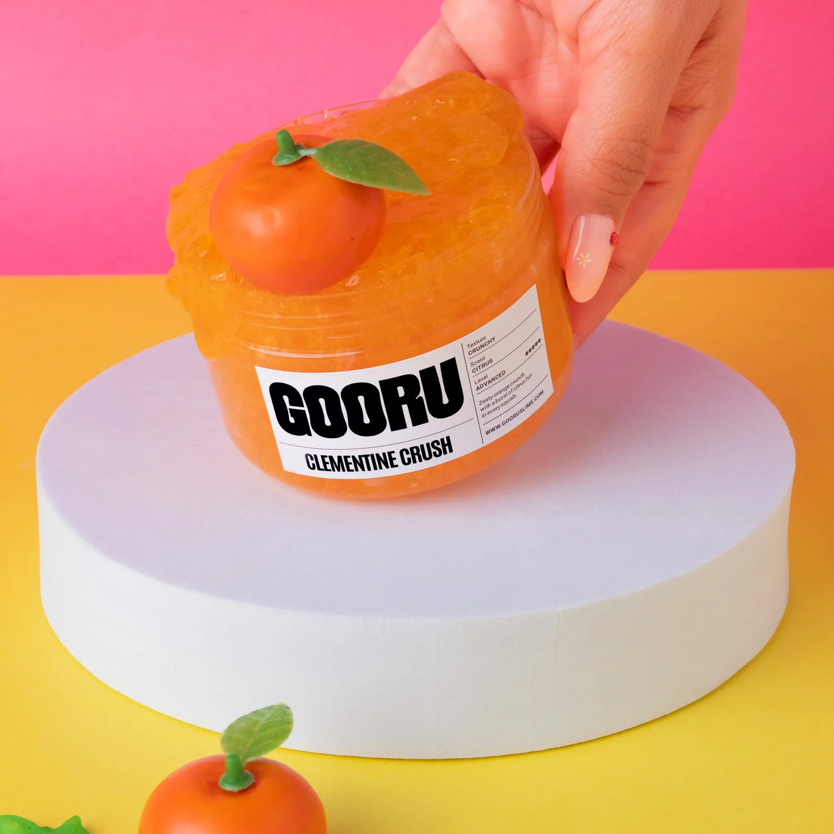 Orange fruit-shaped container with 'GOORU' branding on a colorful background