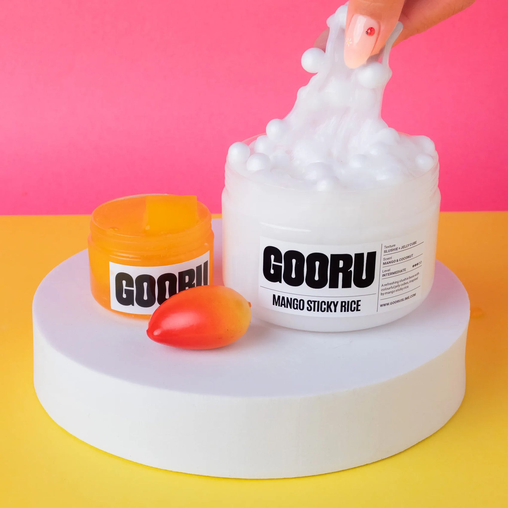 GOORU Mango Sticky Rice slime with a hand squeezing it on a colorful background