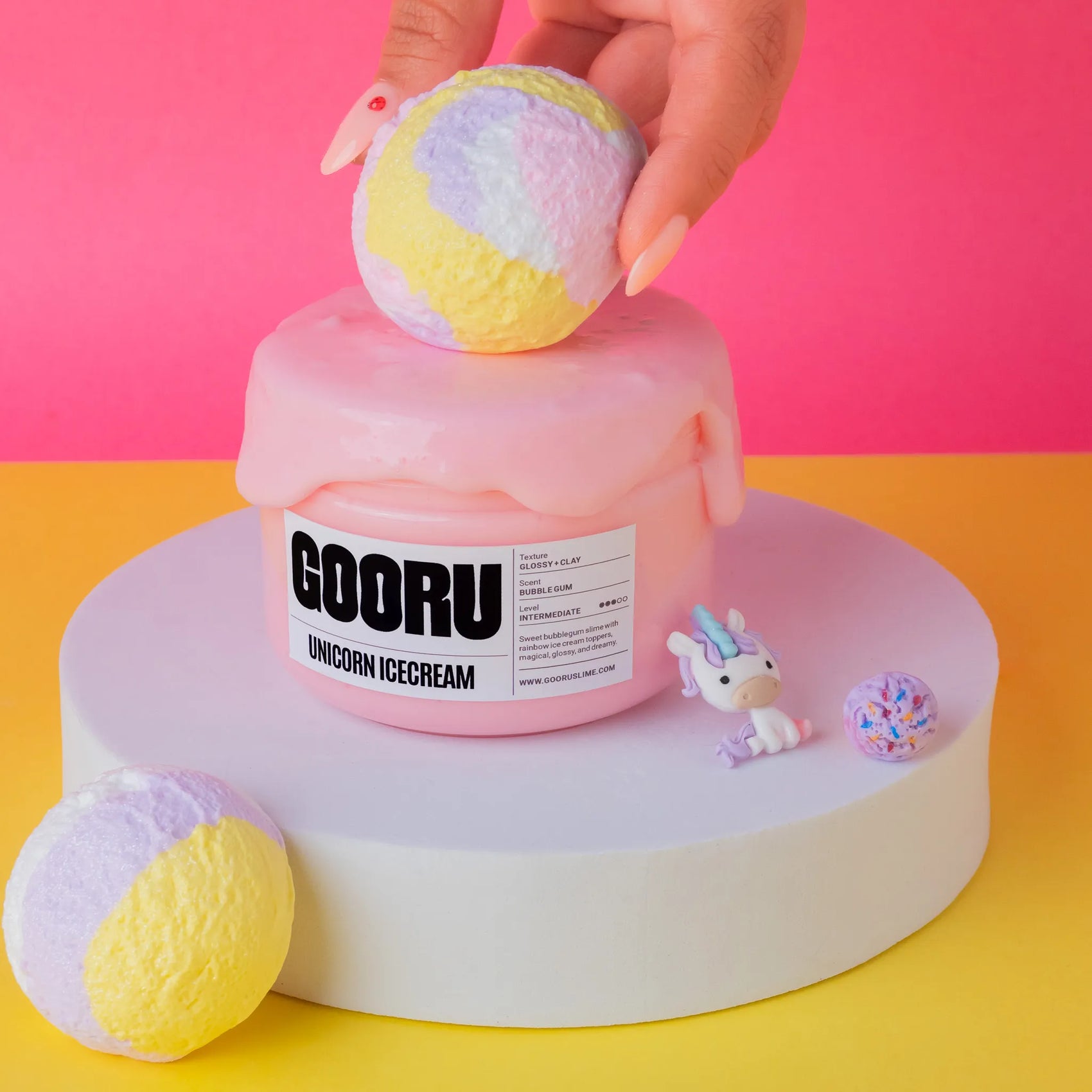 Pink slime resembling a cake with 'GOORU' branding, on a pink and yellow background.