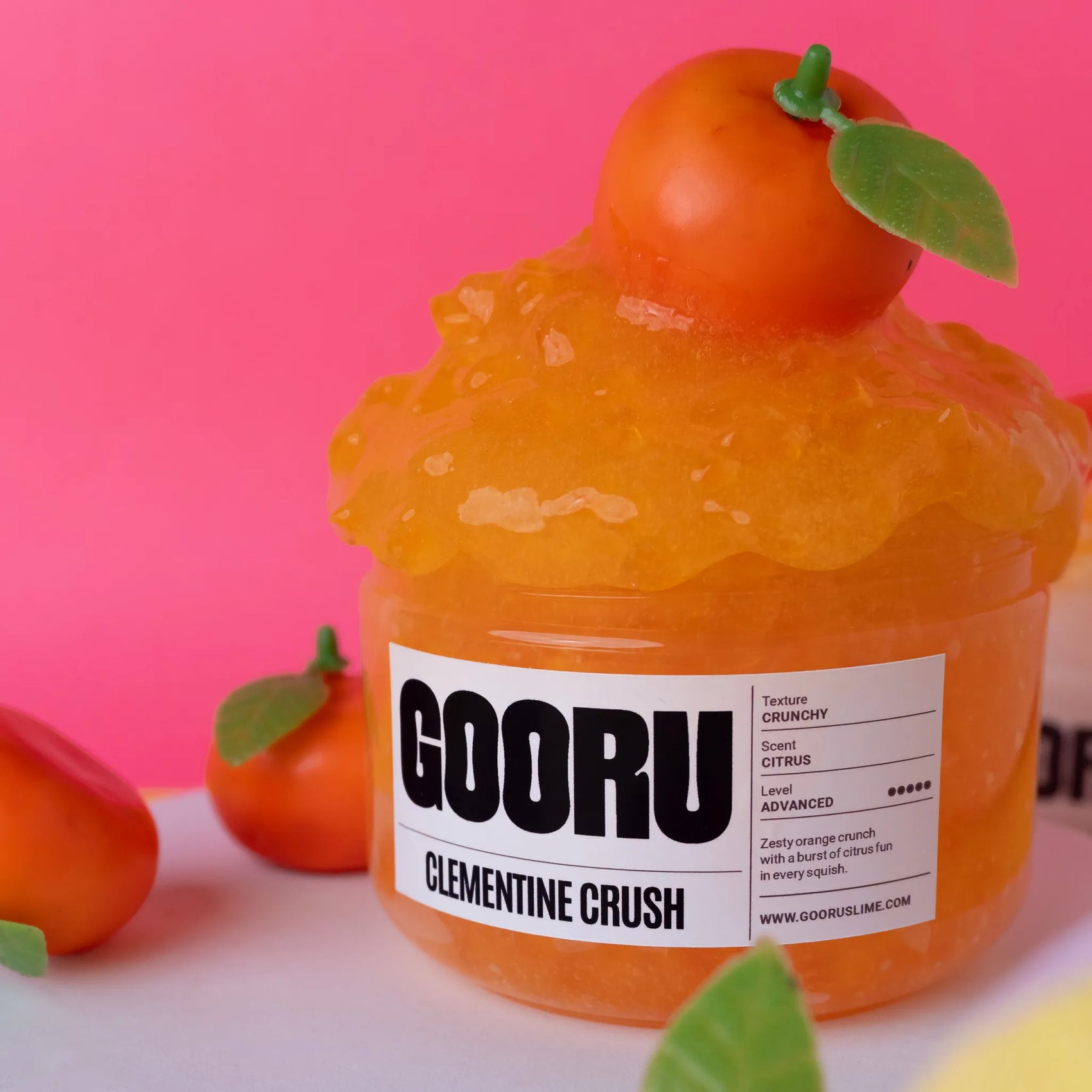 Orange slime product with 'GOORU' label and clementine on top against a pink background
