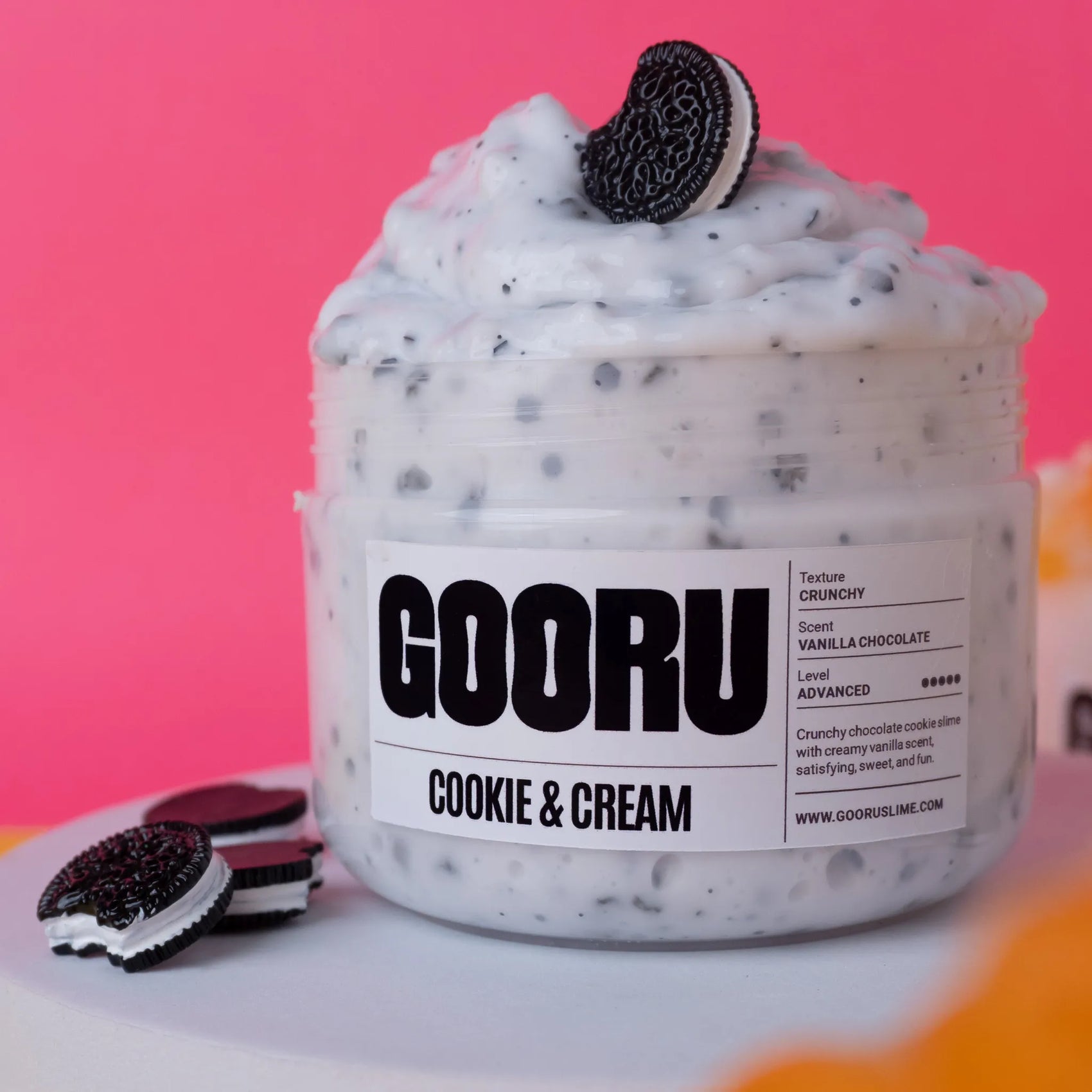 Jar of GOORU cookie and cream product with Oreo cookies on a pink background