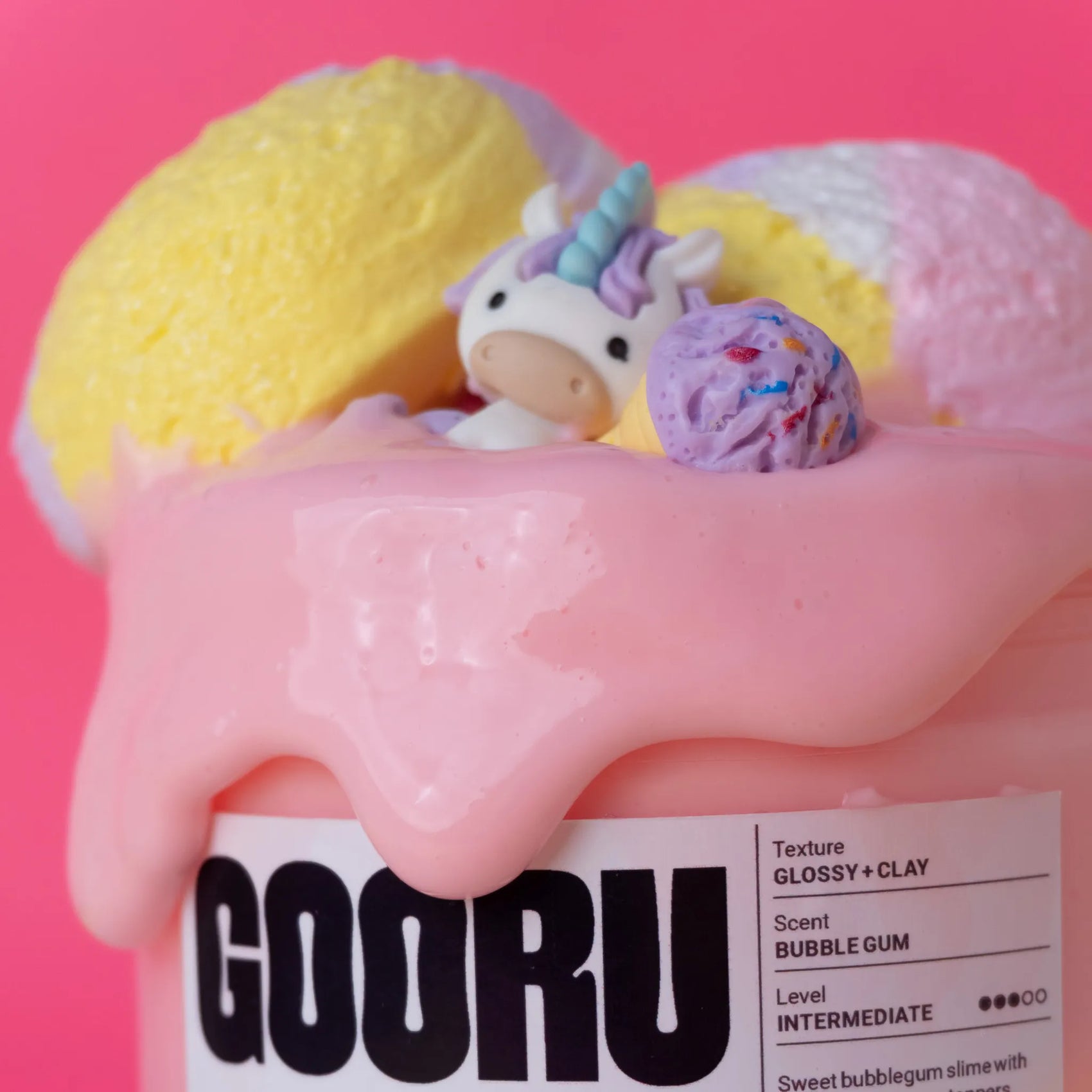 Pink slime with a small plush toy and colorful balls on a pink background, featuring the brand 'GOORU'.