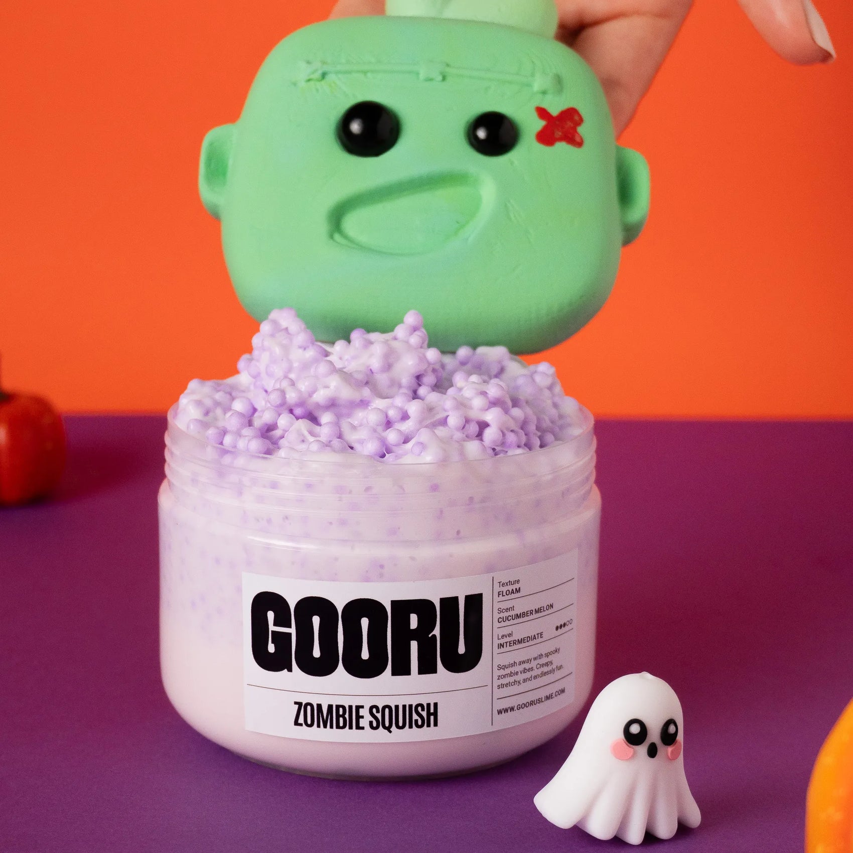 Green zombie squish toy on top of a container labeled 'GOORU Zombie Squish' with a purple background.