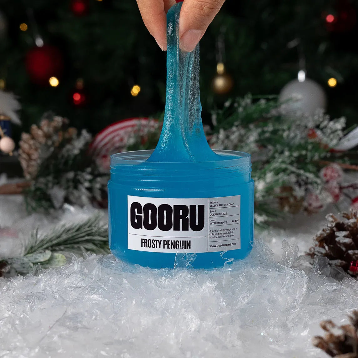 Blue slime being stretched from a container labeled 'GOORU Frosty Penguin' with a festive background.