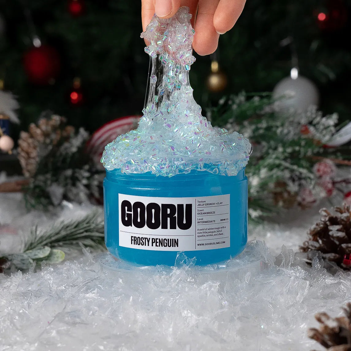 Blue slime being stretched from a container labeled 'GOORU Frosty Penguin' with a festive background.