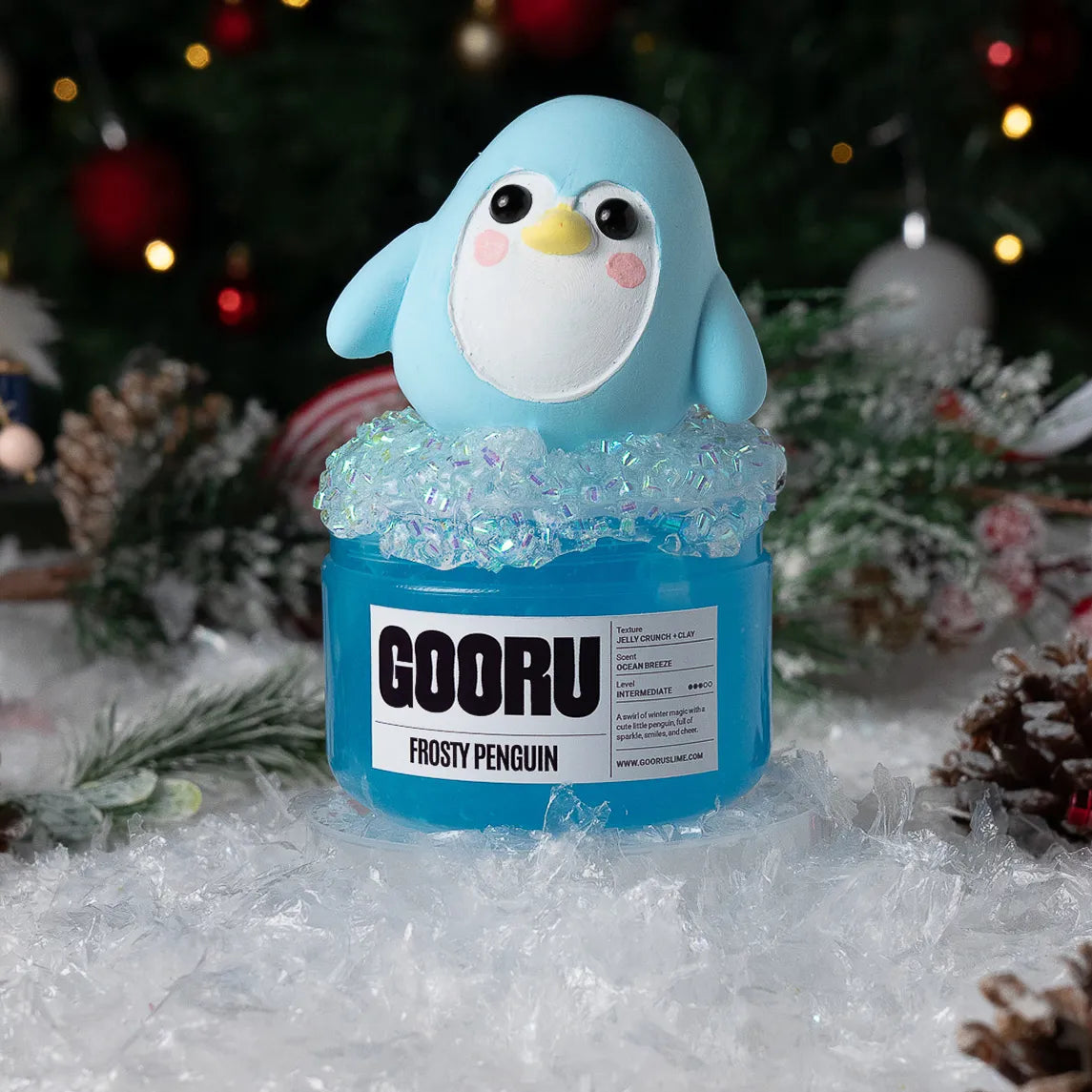 Blue penguin figurine on a jar labeled 'GOORU Frosty Penguin' with a festive background.