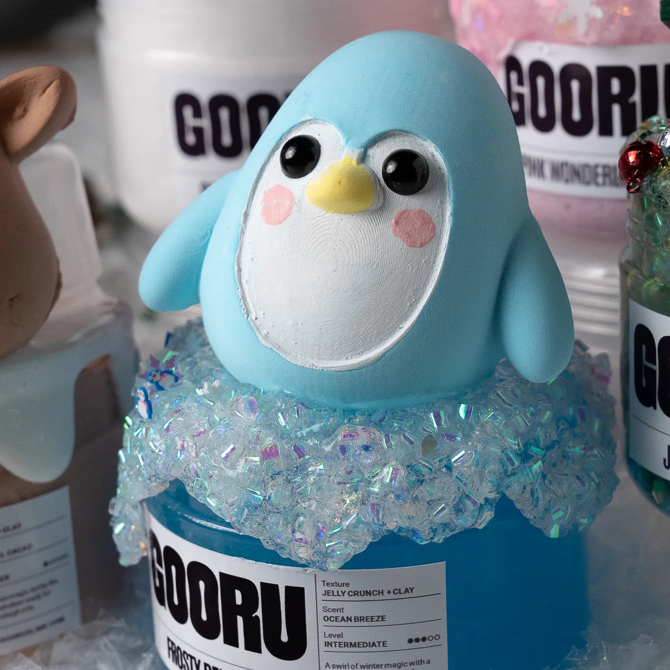Blue penguin-shaped container with 'GOORU' branding on a blurred background